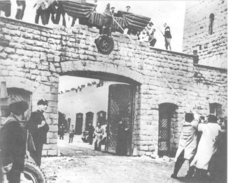 Befreite Häftlinge bei der Demontage des Reichsadlers über der Einfahrt zum Garagenhof des Lagers Mauthausen, 5. Mai 1945. (Foto: US Signal Corps)
