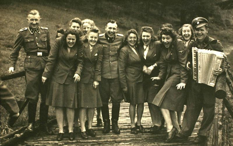 Nazi officers and female auxiliaries pose on a wooden bridge in Solahuette