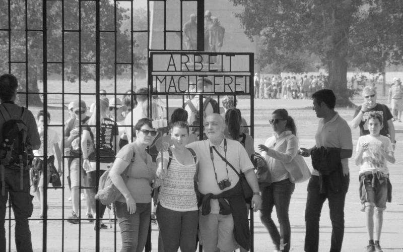 Menschen posieren vor dem Schriftzug "Arbeit macht frei"