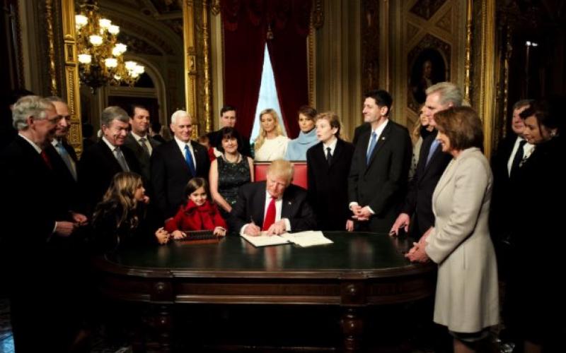 Trump am Schreibtisch umringt von Familie und Stab
