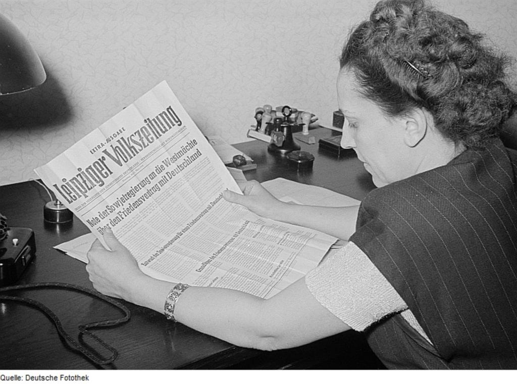 Porträt von Margarete Däumichen, die eine am 11. März 1952 zur Stalin-Note erschienene Sonderausgabe der Leipziger Volkszeitung liest.