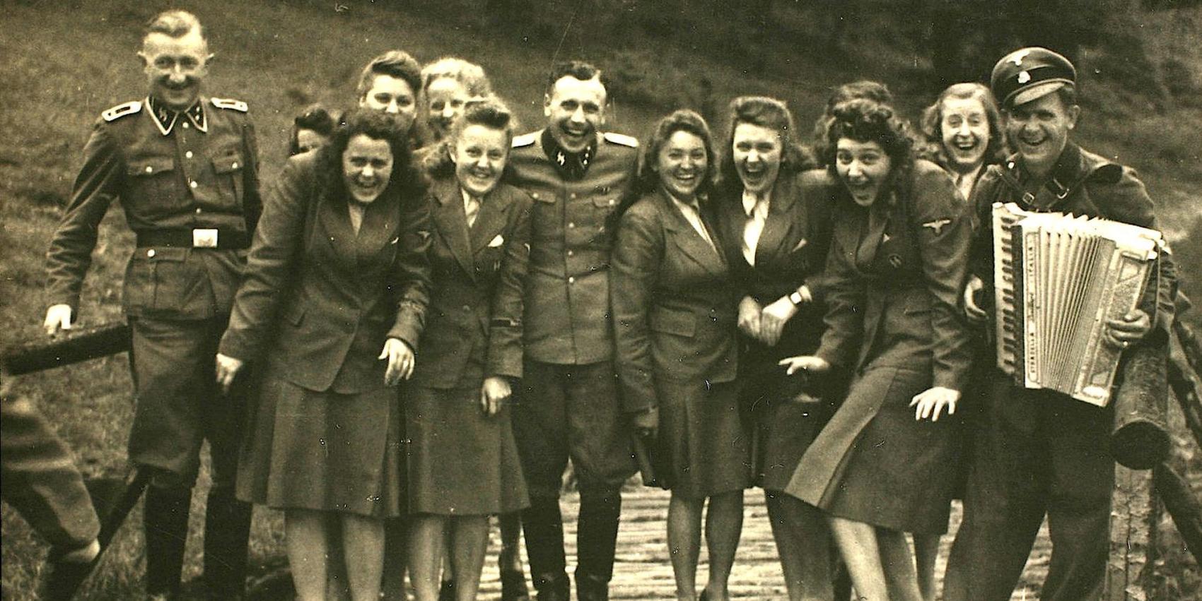 Nazi officers and female auxiliaries pose on a wooden bridge in Solahuette