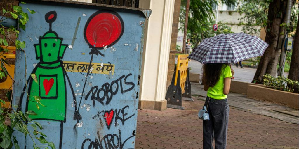 Links ein Graffiti mit der Aufschrift "Robots take control", rechts eine junge Frau mit Regenschirm