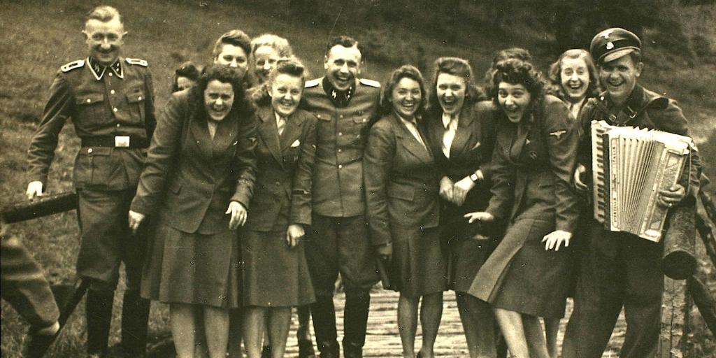 Nazi officers and female auxiliaries pose on a wooden bridge in Solahuette