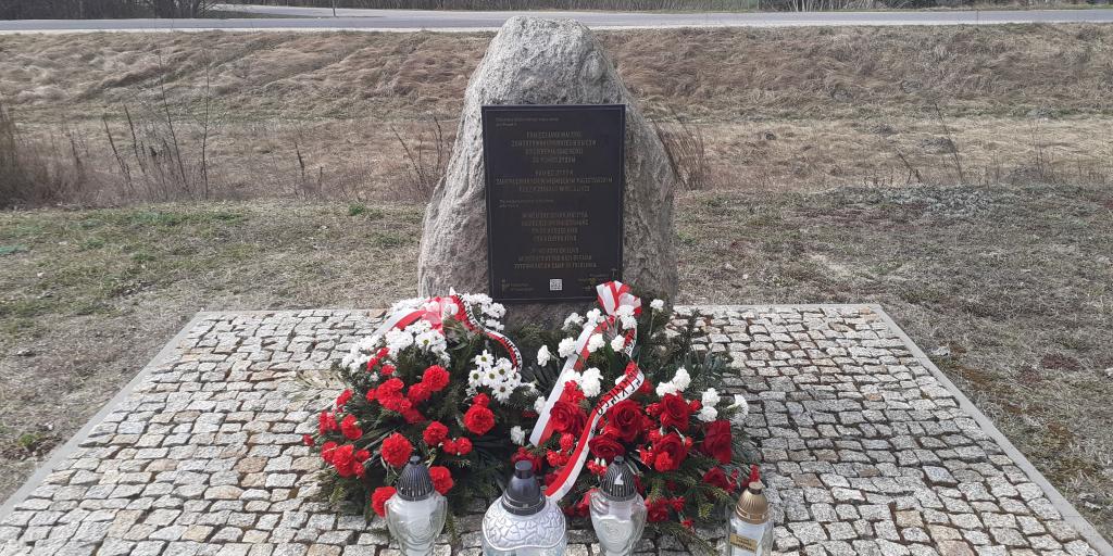 Denkmal an dem Ort der ehemaligen Bahnhofsstation im Dorf Treblinka, 31. März 2026. Die Kränze wurden vom Pilecki Institut (Witold Pilecki Institute of Solidarity and Courage) und vom Bürgermeister und den Bewohnern der Gemeinde Małkinia gestiftet; rechts eine goldene Kerze mit der goldenen Inschrift „Treblinka Museum – wir erinnern” 