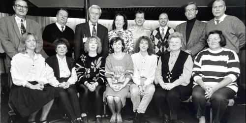 Das Bild zeigt ostdeutsche Mitarbeitende der „DAAD-Arbeitsstelle Berlin-Mitte“ (ASBM) mit dem westdeutschen Leiter des Büros (3. von links oben) auf einem Betriebsausflug in Rostock 1993. 