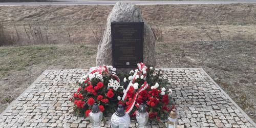 Denkmal an dem Ort der ehemaligen Bahnhofsstation im Dorf Treblinka, 31. März 2026. Die Kränze wurden vom Pilecki Institut (Witold Pilecki Institute of Solidarity and Courage) und vom Bürgermeister und den Bewohnern der Gemeinde Małkinia gestiftet; rechts eine goldene Kerze mit der goldenen Inschrift „Treblinka Museum – wir erinnern” 